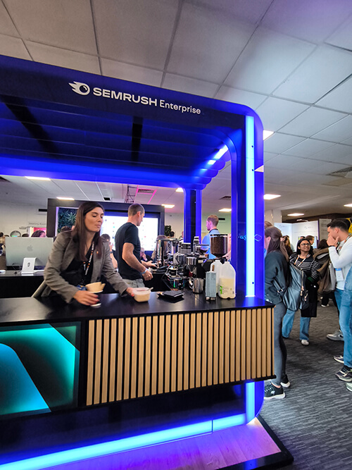Semrush baristas making coffee for a long line of people at BrightonSEO 2024