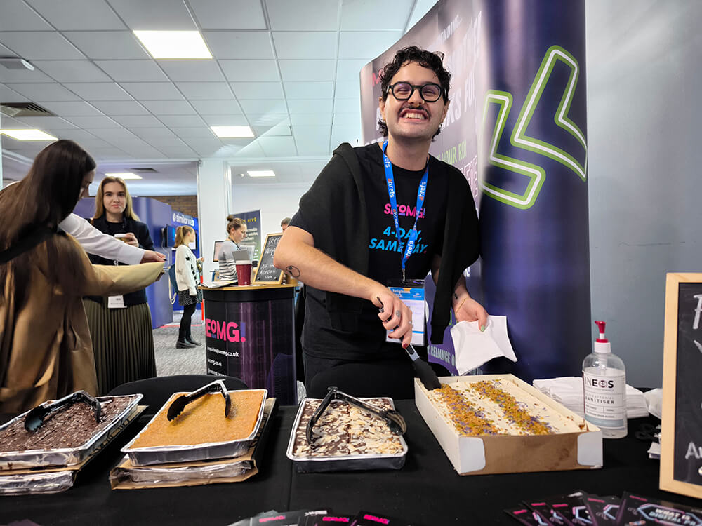 A conference attendee from marketing agency handing out one of four vegan cakes at the BrightonSEO 2024 conference